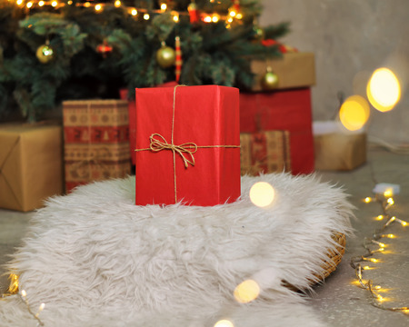 A Big Red Gift Stands Under The Christmas Tree Background For Holiday Stock A Big Red Gift Stands Under The Christmas Tree Background For Holiday Stock