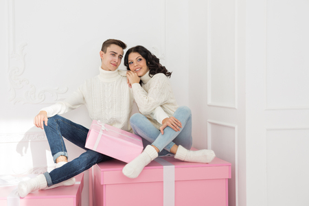 Loving Couple Teenagers Sitting On Gifts They Are Wearing The Same White Sweaters Holidays Loving Couple Teenagers Sitting On Gifts They Are Wearing The Same White Sweaters Holidays