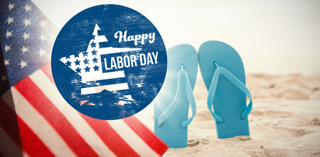 Digital composite image of happy labor day text on blue poster against blue flip flop in sand