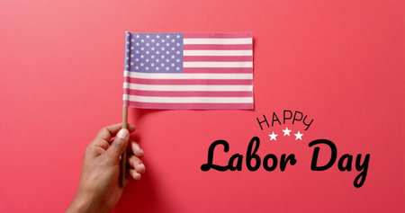 Image of happy labor day text and hand holding flag of usa on red background patriotism and celebration concept digitally generated image
