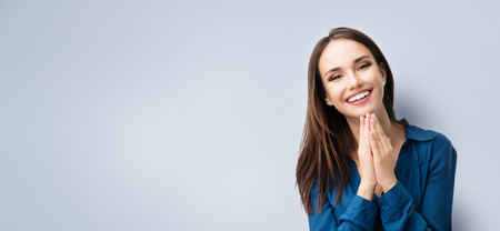 Retrato de feliz gesuring joven sonriente en ropa azul elegante casual, sobre fondo gris, con el área de copyspace para advertisiment, texto o lema. Concepto de publicidad. Composición de banner horizontal. Foto de archivo - 78084975