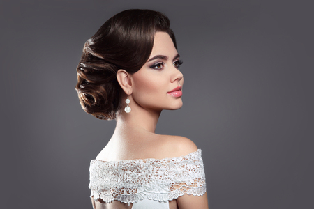 レトロな女性のブルネットの美しさの肖像画 髪型とメイクとエレガントな女性は 真珠のイヤリングの宝石類ポーズ スタジオ灰色の背景に分離されました の写真素材 画像素材 Image