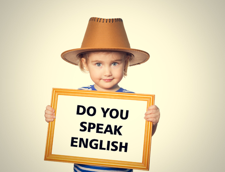 Little Funny girl in striped shirt with blackboard. Text do you speak english. Stock Photo