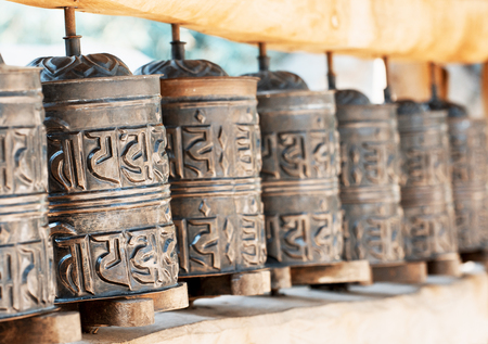A prayer wheel is a cylindrical wheel on a spindle made from metal, wood, stone, leather or coarse cotton. teal and orange photo filter.