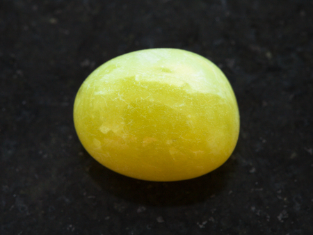 天然鉱物岩石 黒御影石の背景に磨かれた黄色いカルサイト宝石のマクロ撮影 の写真素材 画像素材 Image