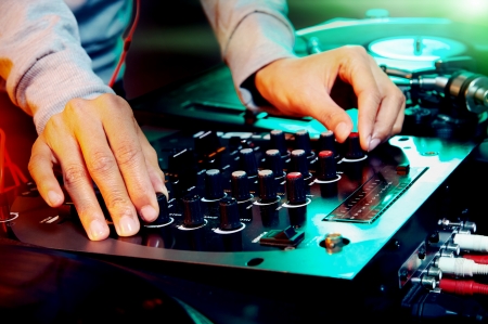 dj hands on equipment deck and mixer with vinyl record at party