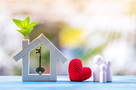 Modèle de maison avec plante en croissance et clés de maison et coeur rouge et modèle familial mis sur le vieux bois dans le parc public, prêt et investissement commercial pour la propriété du concept immobilier. Banque d'images