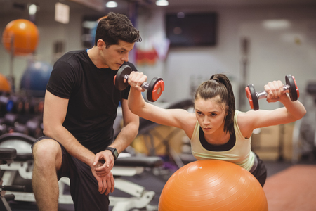 Fit woman working out with trainer at the gym