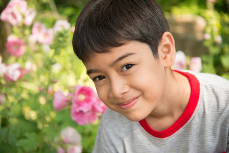 Little boy smelling flower in the park Фото со стока