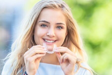 Koncepcja ortodoncji invisalign - młoda atrakcyjna kobieta trzyma - za pomocą niewidocznych szelek lub trenera.