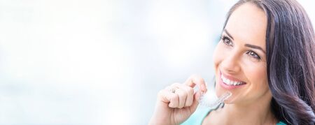 Koncepcja ortodoncji invisalign - młoda atrakcyjna kobieta trzyma - za pomocą niewidocznych szelek lub trenera. Zdjęcie Seryjne