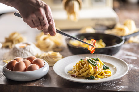 Fettuccine au basilic frais dressé en mettant un morceau de bacon cuit dessus avec une pince à épiler.