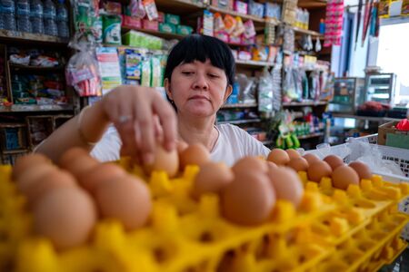 Femmes indonésiennes asiatiques organisant des œufs à l'intérieur d'un petit magasin familial local, ou appelé localement warung. l'emplacement est à tasikmalaya, en indonésie. mise au point sélective.