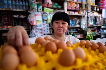 Femmes indonésiennes asiatiques organisant des œufs à l'intérieur d'un petit magasin familial local, ou appelé localement warung. l'emplacement est à tasikmalaya, en indonésie. mise au point sélective.