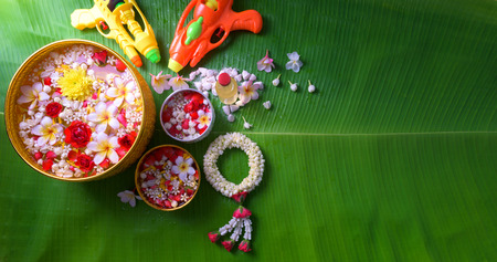 Thai traditional jasmine garland and Colorful flower in water bowls decorating and scented water, perfume, marly limestone, pipe gun on Banana leaf for Songkran Festival or Thai New Year. Фото со стока