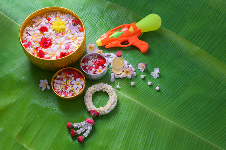 Thai traditional jasmine garland and Colorful flower in water bowls decorating and scented water, perfume, marly limestone, pipe gun on Banana leaf for Songkran Festival or Thai New Year. Фото со стока
