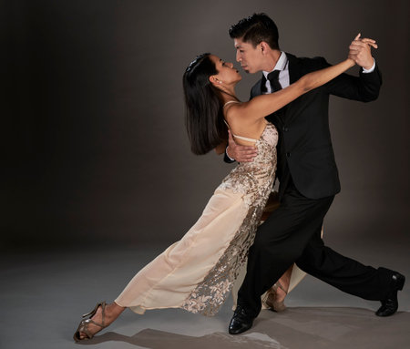タンゴ社交ダンスを踊るラテン女性とアジア人男性。スタジオショットの