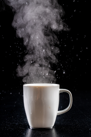 White mug and water vapor. freshly brewed hot drink. black background.