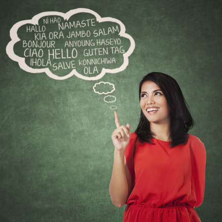 Portrait of female high school student pointing at cloud bubble of multi language. Concept of multi language learning