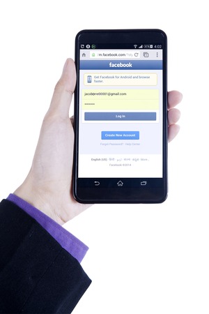 logo samsung: JAKARTA, SEPTEMBER 08, 2015: Closeup of businessman hand using a smartphone to open facebook login page biên tập