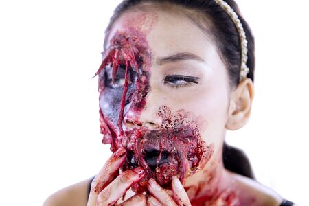 Close up of a horrible female zombie with wounds on her face, isolated on white background