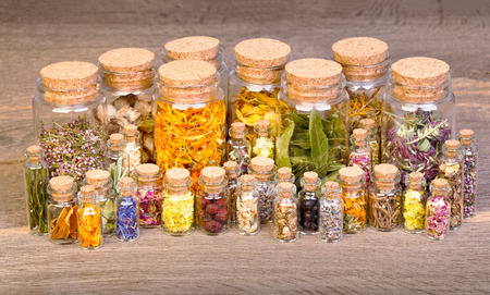 Healing herbs in bottles for herbal medicine on old wooden table.