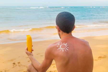 Mężczyzna na plaży z kremem do opalania na plecach. selektywne skupienie. podróż. Zdjęcie Seryjne