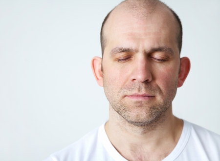 portrait of positive bald headed smiling man on white background