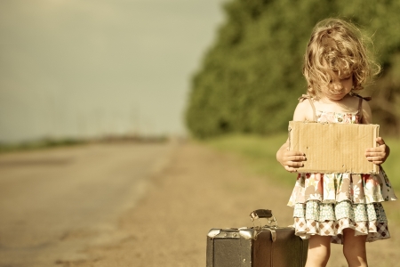 sad lonely: Lonely girl with suitcase standing about road and holding paper with copyspace in hands