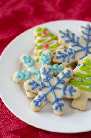 Snowflake And Christmas Tree Shaped Sugar Cookies Decorated With Icing On A White Plate Stock Photo Snowflake And Christmas Tree Shaped Sugar Cookies Decorated With Icing On A White Plate Stock Photo