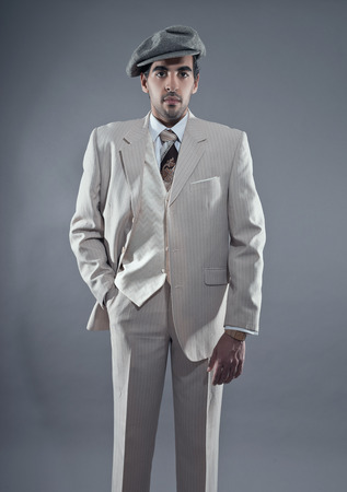 マフィア ファッションの男が白いストライプのスーツとグレーのキャップを身に着けています スタジオ撮影します の写真素材 画像素材 Image