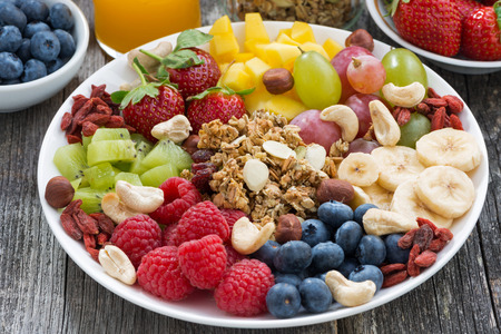 ingredients for a healthy breakfast - berries, fruit and muesli on wooden table, close-up, horizontal - 38994076