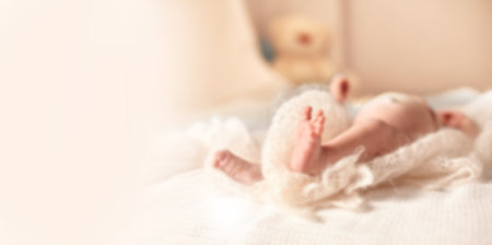 Image of a newborn baby lying on the couch in the nursery background for text with a child in a blur Stock Photo