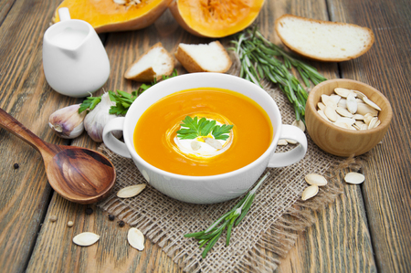 a carrot: Bí ngô súp nhuyễn với gia vị trên một chiếc bàn gỗ