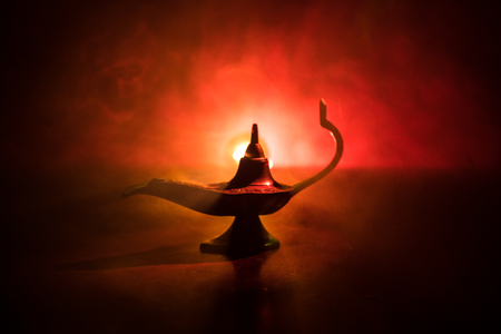 Antique aladdin arabian nights genie style oil lamp with soft light white smoke dark background lamp of wishes concept selective focus