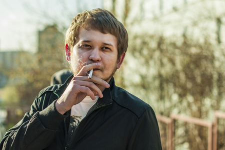 若い男顔開いて息を吐き出すタバコの開口のクローズ アップから煙にひげと流行に敏感な喫煙者 の写真素材 画像素材 Image