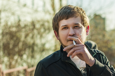 若い男顔開いて息を吐き出すタバコの開口のクローズ アップから煙にひげと流行に敏感な喫煙者 の写真素材 画像素材 Image