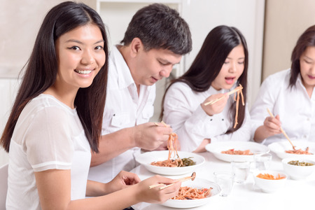Familienmittagessen. Asiatische Familie am modernen Mittagessen zusammen essen