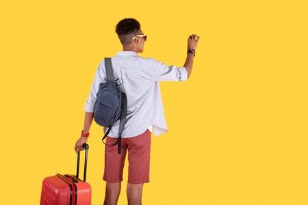 My home joyful positive man looking at the front door while holding his suitcase