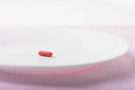 Miracle diet pill on a white plate shallow depth of field Stock Photo