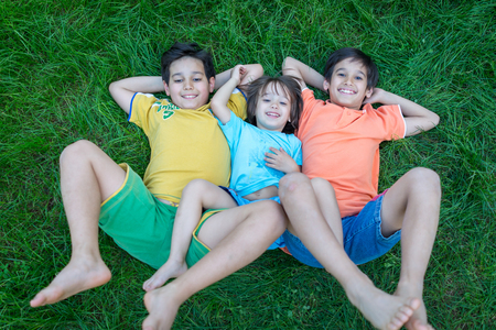 Group Of Cute Happy Children In Summer Lying On Green Grass With Feet Up Stock Photo Group Of Cute Happy Children In Summer Lying On Green Grass With Feet Up Stock Photo